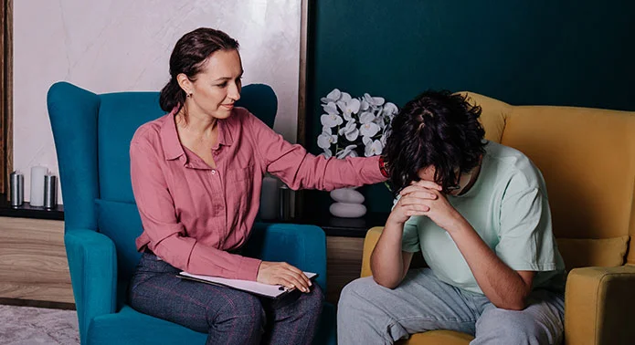 A boy is getting encouraged by therapist in a CBT session