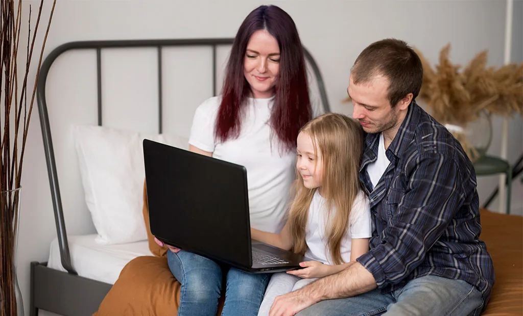 A parent and teen sit close together at home, looking at a screen calmly side by side